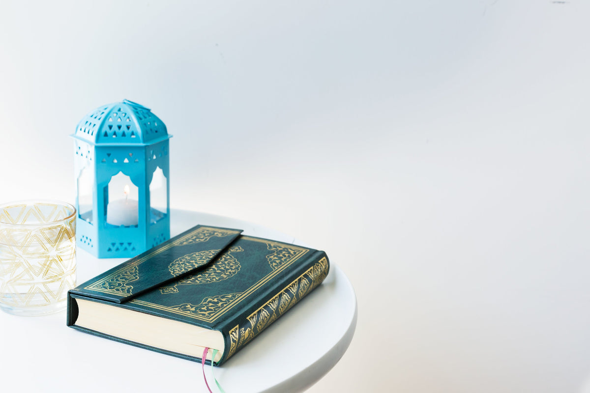 A lit lantern beside a glass of water on a table